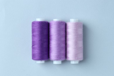 Photo of Spools of colorful sewing threads on light background, flat lay