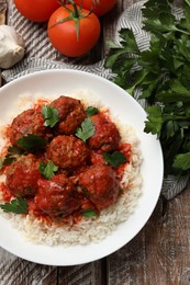 Photo of Tasty meatballs with sauce, rice and products on wooden table, flat lay