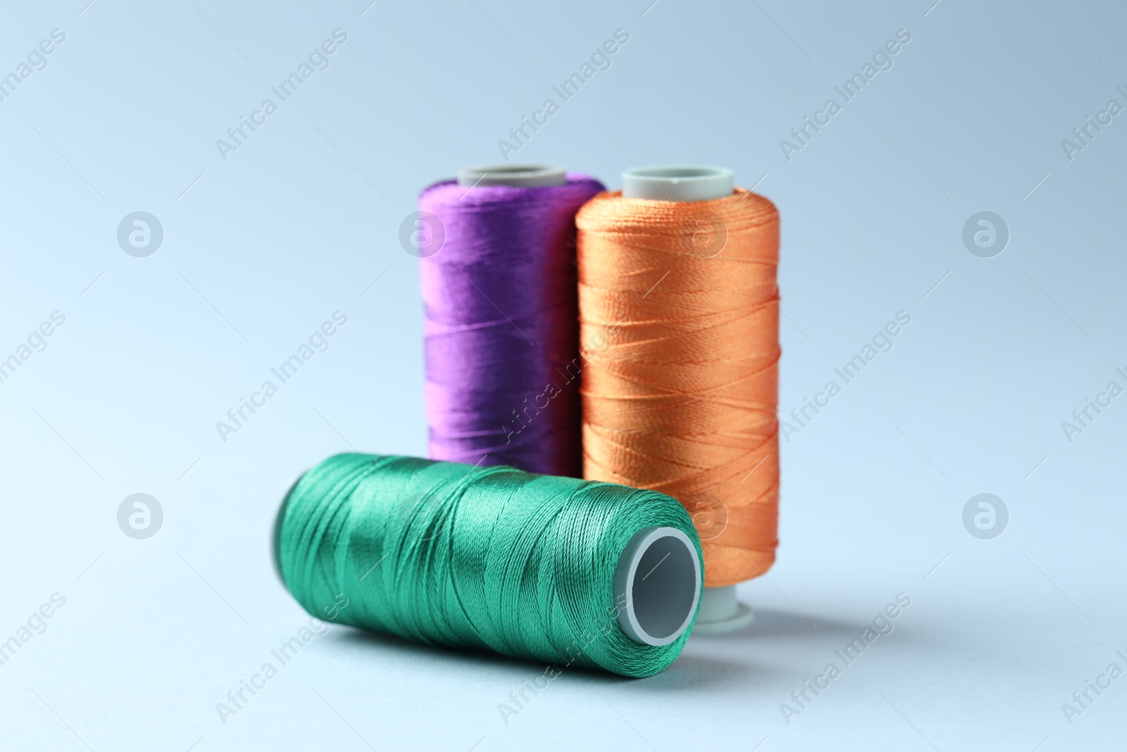 Photo of Spools of colorful sewing threads on light background