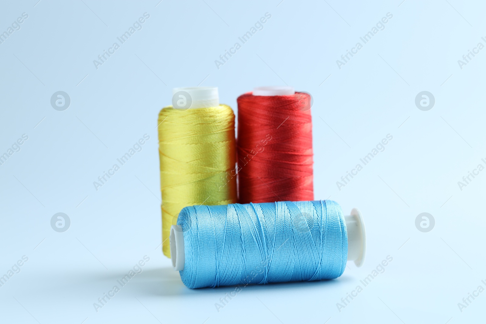 Photo of Spools of colorful sewing threads on light background