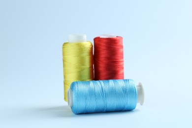 Photo of Spools of colorful sewing threads on light background