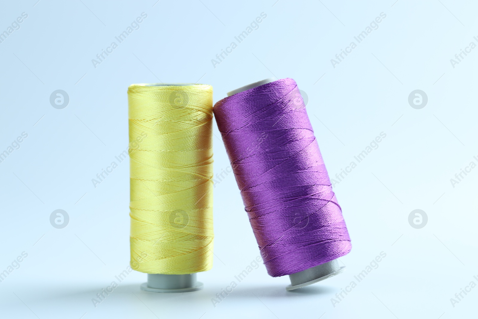 Photo of Spools of colorful sewing threads on light background