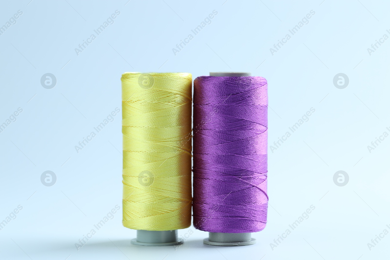 Photo of Spools of colorful sewing threads on light background