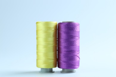 Photo of Spools of colorful sewing threads on light background