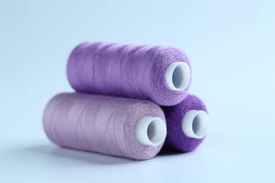 Photo of Spools of colorful sewing threads on light background, closeup