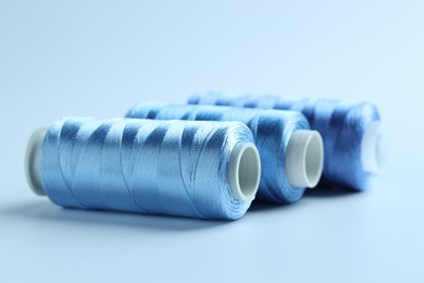 Photo of Spools of sewing threads on light background, closeup