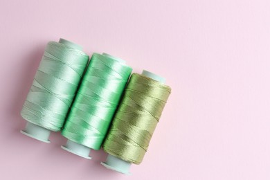 Photo of Spools of colorful sewing threads on pink background, flat lay. Space for text