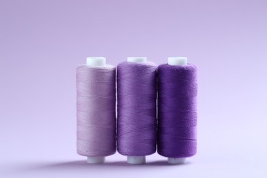 Photo of Spools of colorful sewing threads on lilac background