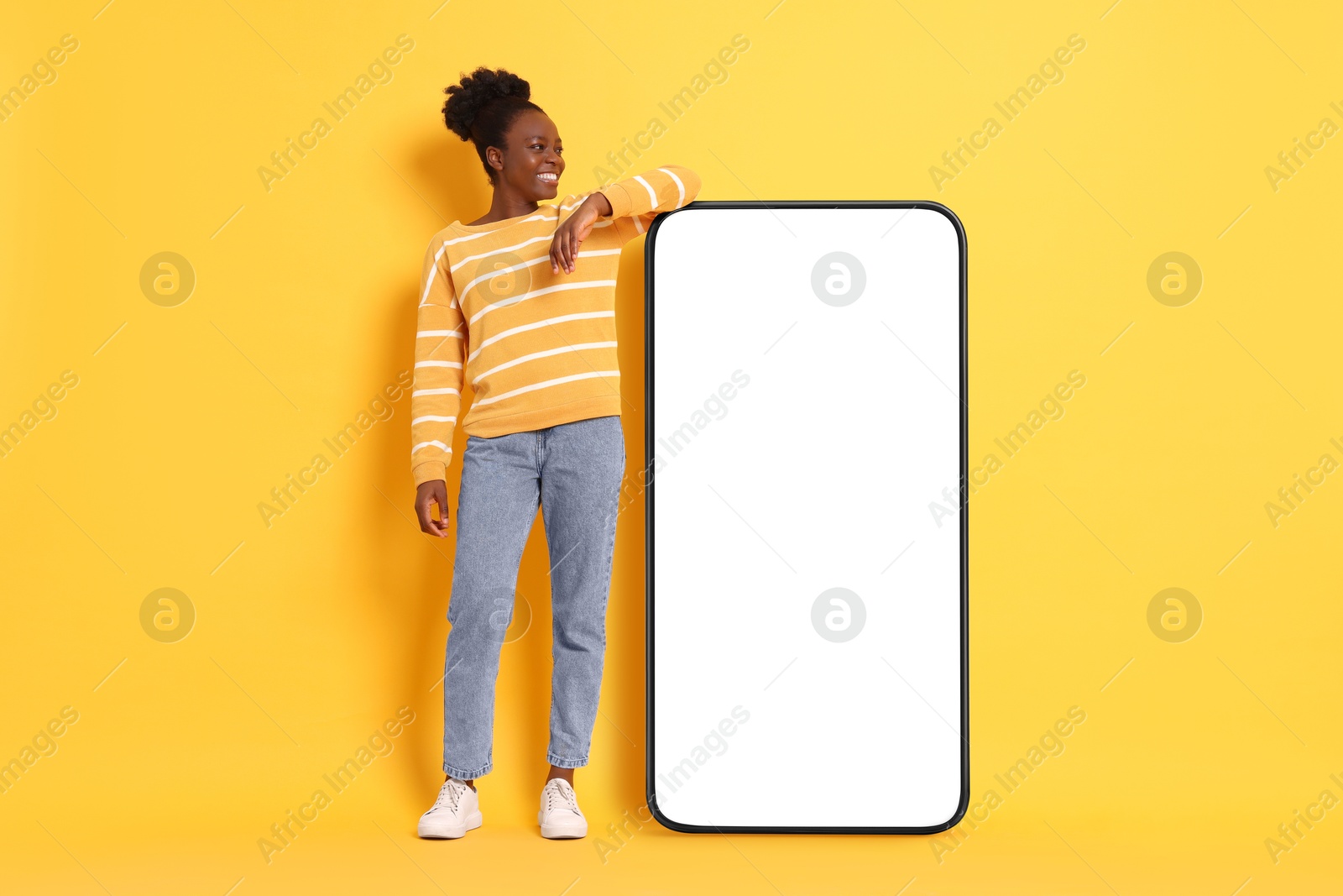 Image of Happy woman leaning on big mobile phone with blank screen on orange background