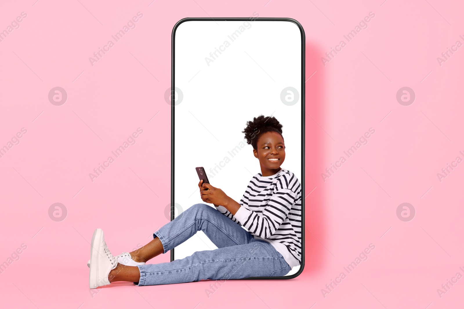 Image of Happy woman with smartphone sitting in big mobile phone on pink background