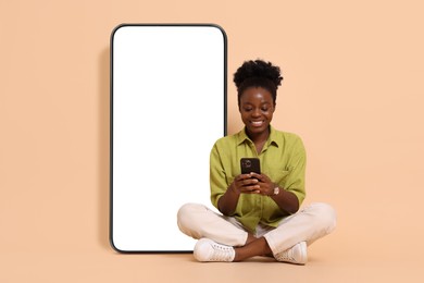 Image of Happy woman with smartphone sitting on beige background. Big mobile phone with blank screen behind her