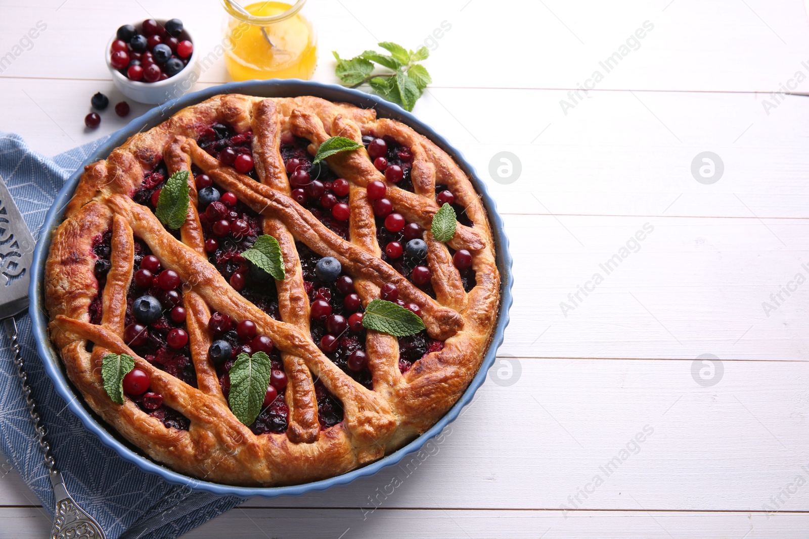 Photo of Delicious currant pie and fresh berries on white wooden table, space for text