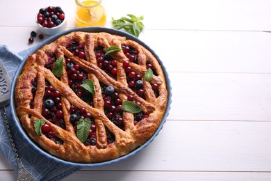 Photo of Delicious currant pie and fresh berries on white wooden table, space for text