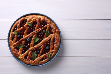 Photo of Delicious currant pie and fresh berries on white wooden table, top view. Space for text