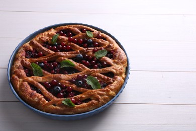 Photo of Delicious currant pie and fresh berries on white wooden table, space for text