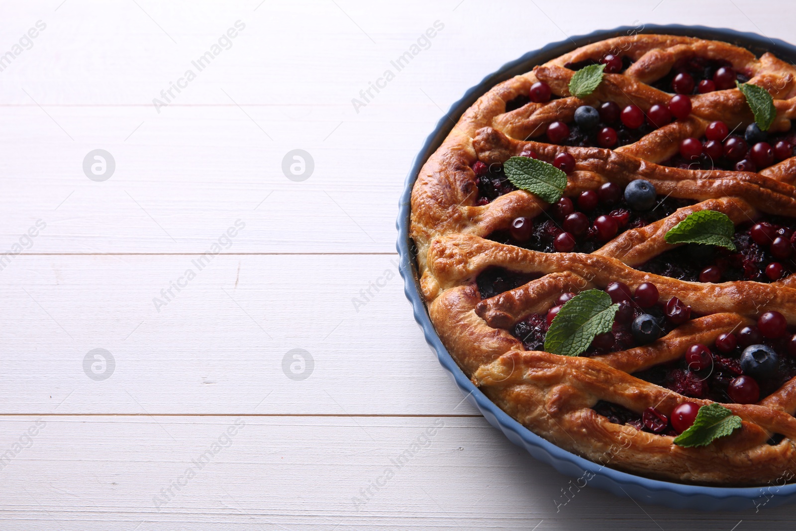 Photo of Delicious currant pie and fresh berries on white wooden table, space for text