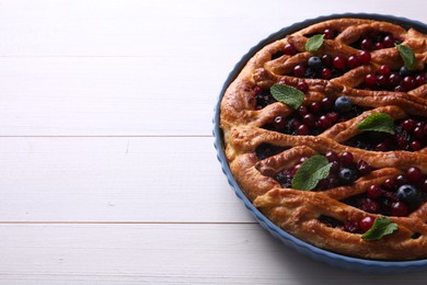 Photo of Delicious currant pie and fresh berries on white wooden table, space for text