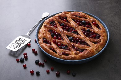 Photo of Delicious currant pie with fresh berries and spatula on grey table