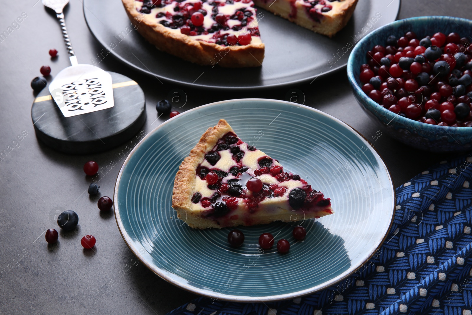 Photo of Piece of delicious currant pie and fresh berries on grey table