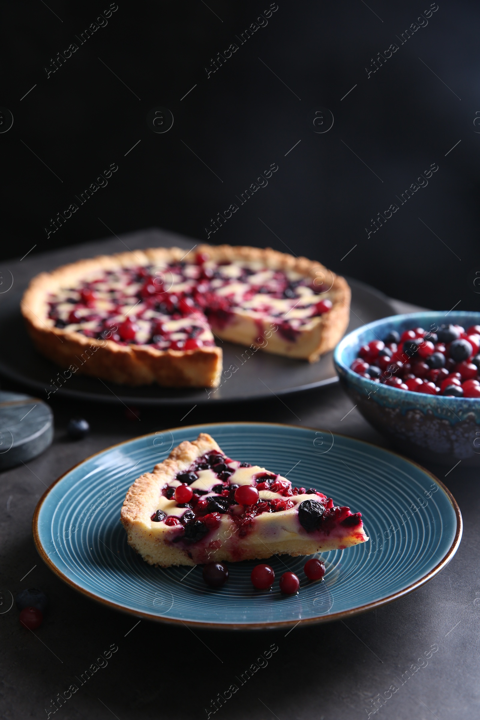 Photo of Piece of delicious currant pie and fresh berries on grey table, space for text