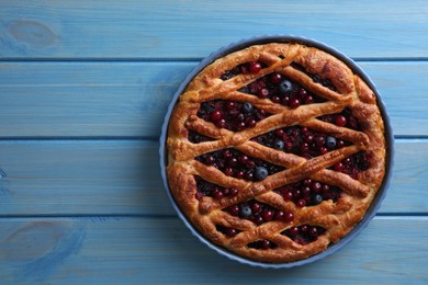 Photo of Delicious currant pie and fresh berries on blue wooden table, top view. Space for text