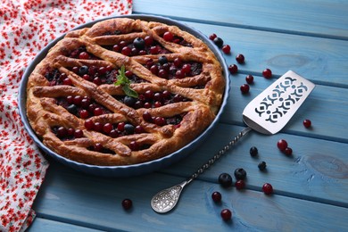 Photo of Delicious currant pie with fresh berries and spatula on blue wooden table