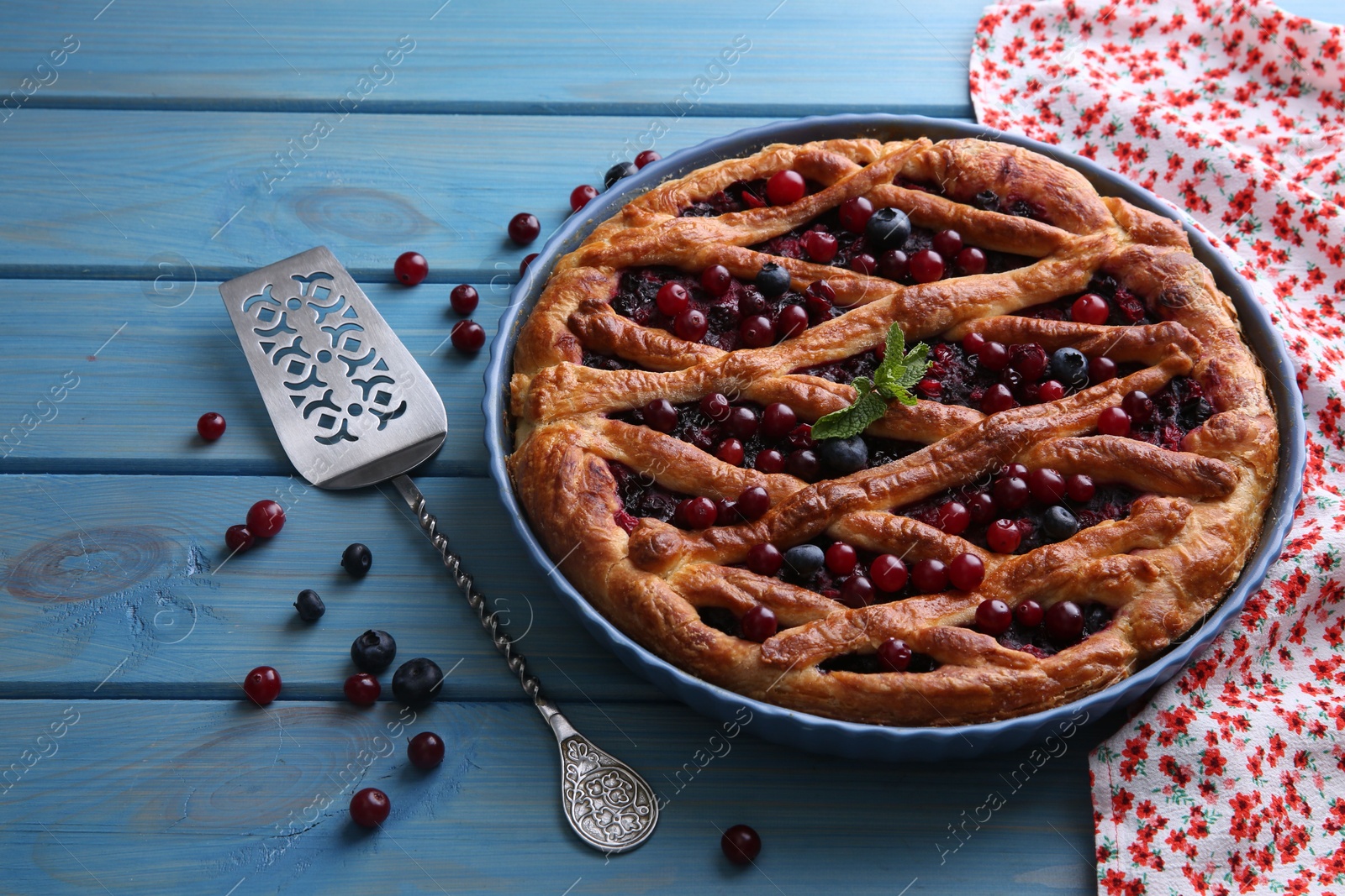 Photo of Delicious currant pie with fresh berries and spatula on blue wooden table