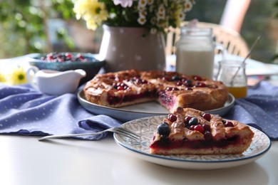 Photo of Piece of delicious currant pie and fresh berries on white table, closeup. Space for text