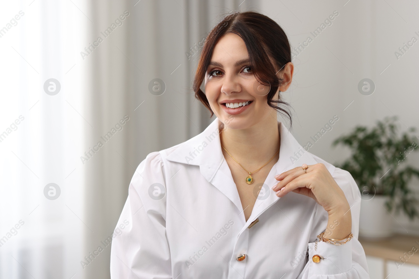 Photo of Beautiful young woman wearing elegant jewelry indoors