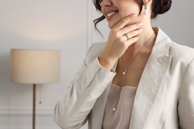 Photo of Woman wearing elegant jewelry indoors, closeup. Space for text