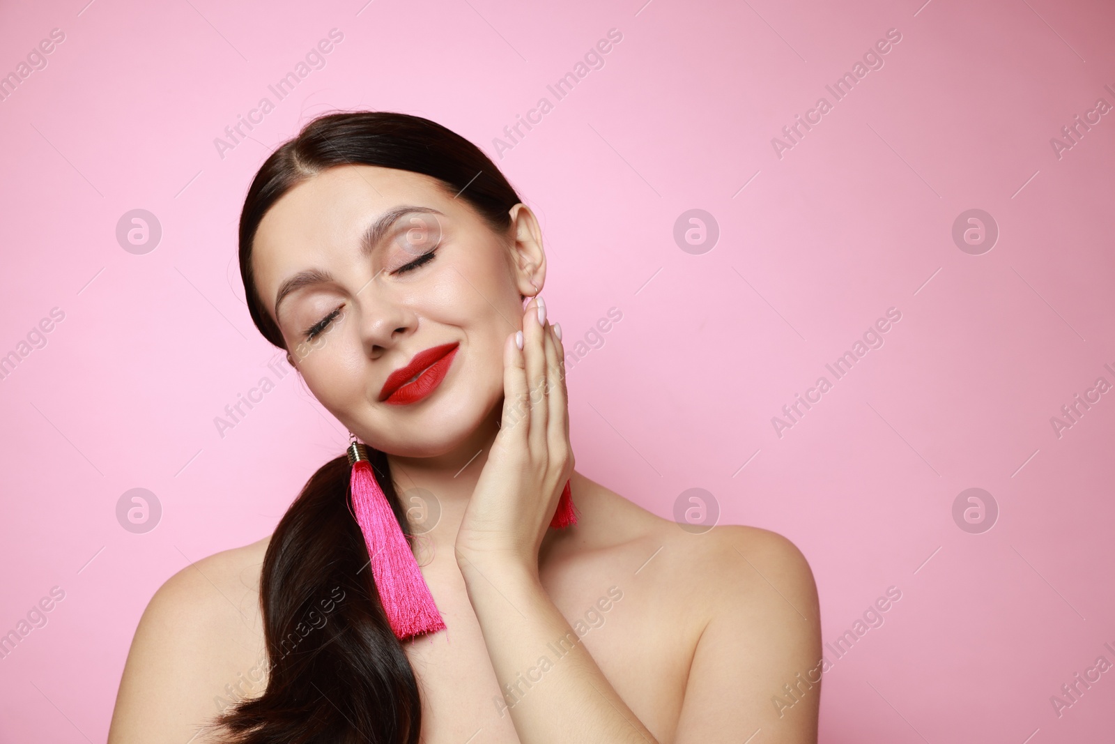 Photo of Beautiful young woman wearing stylish earrings on pink background. Space for text