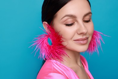 Photo of Beautiful young woman wearing stylish earrings on light blue background, closeup