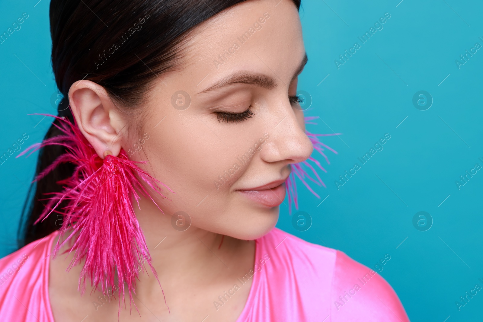 Photo of Beautiful young woman wearing stylish earrings on light blue background, closeup. Space for text