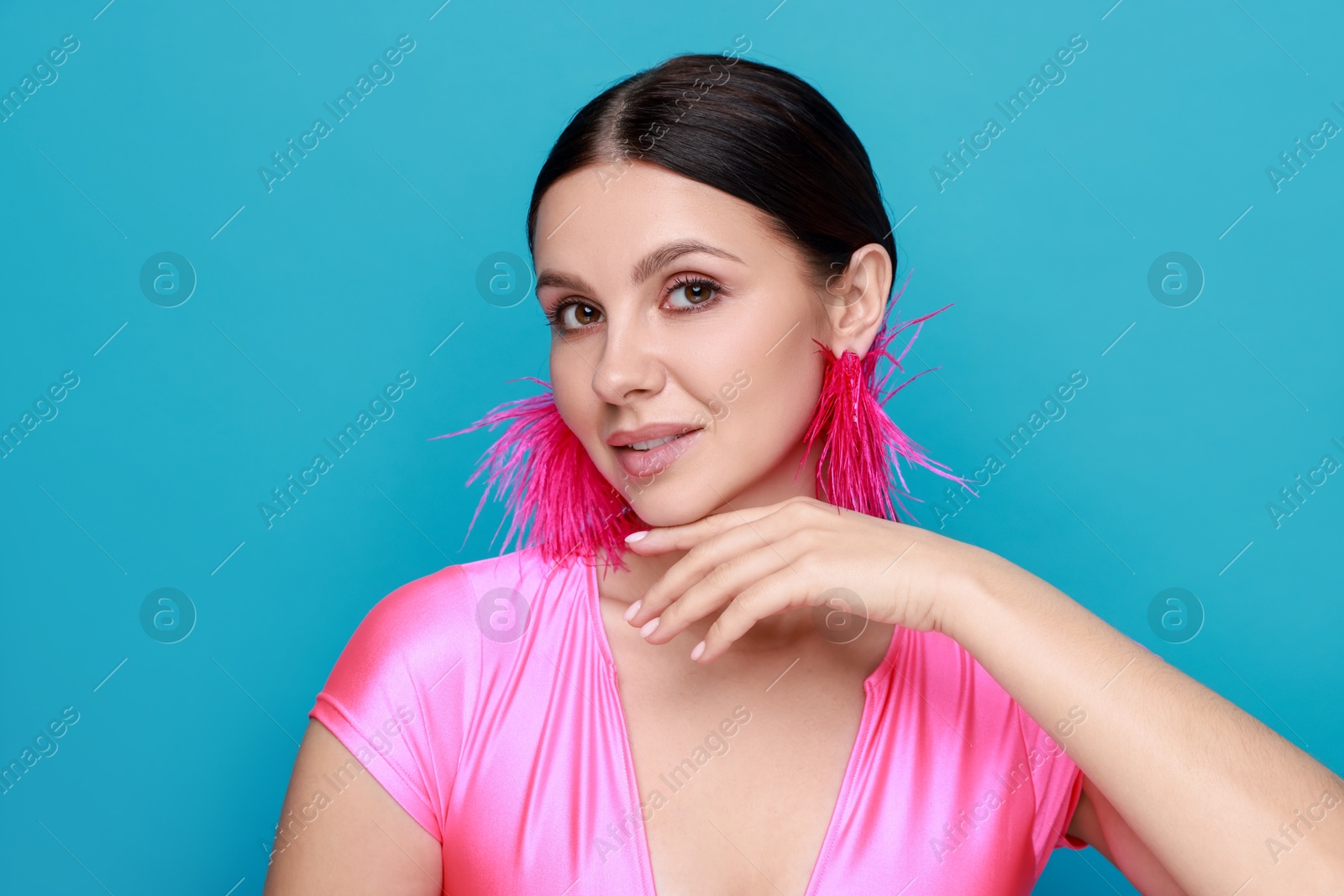 Photo of Beautiful young woman wearing stylish earrings on light blue background