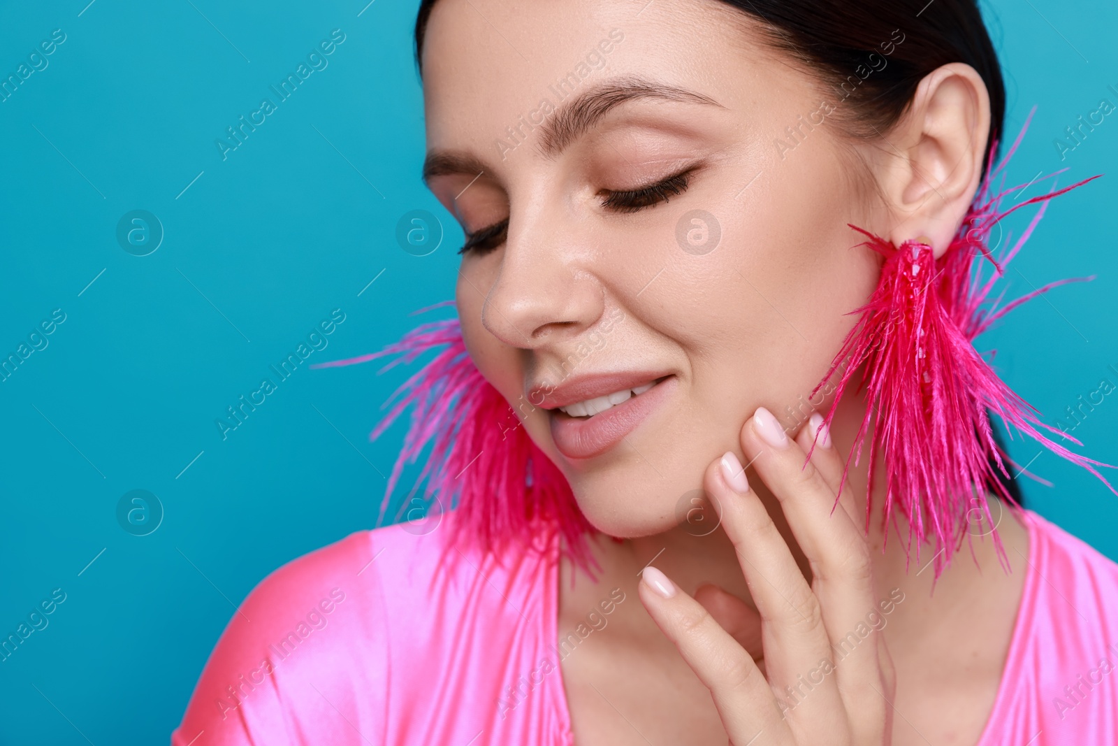 Photo of Beautiful young woman wearing stylish earrings on light blue background, closeup