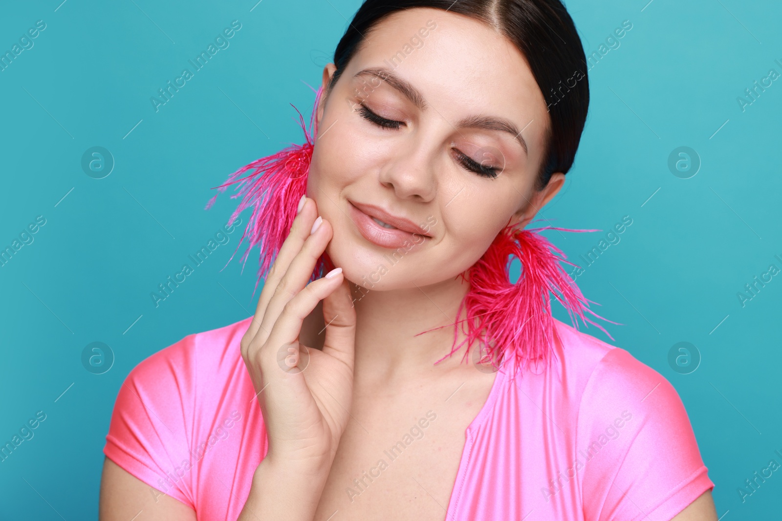 Photo of Beautiful young woman wearing stylish earrings on light blue background