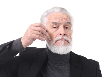 Photo of Senior man applying serum onto his beard on white background