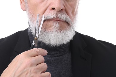 Photo of Senior man trimming beard with scissors on white background, closeup