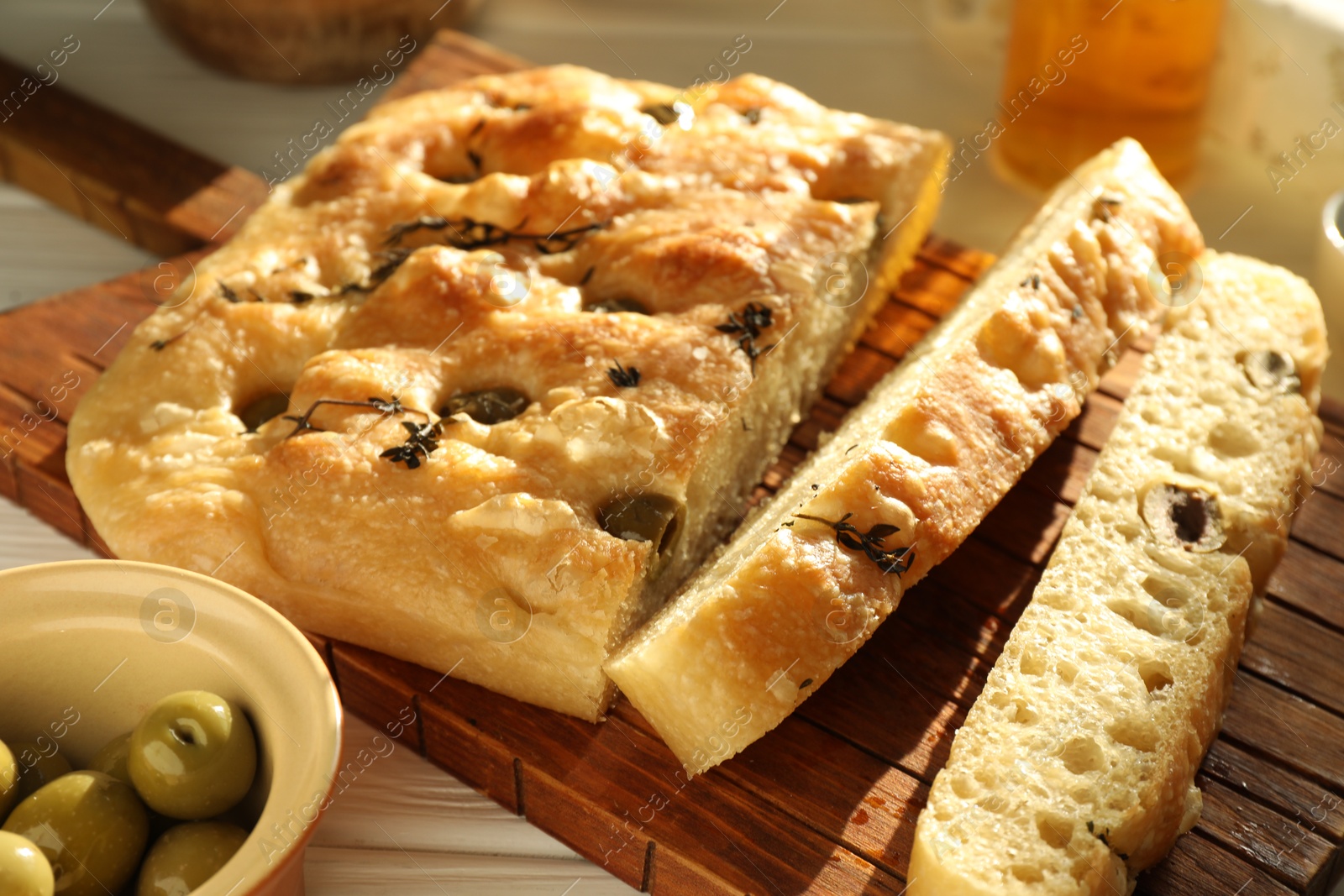 Photo of Pieces of delicious focaccia bread with olives and thyme on table, closeup