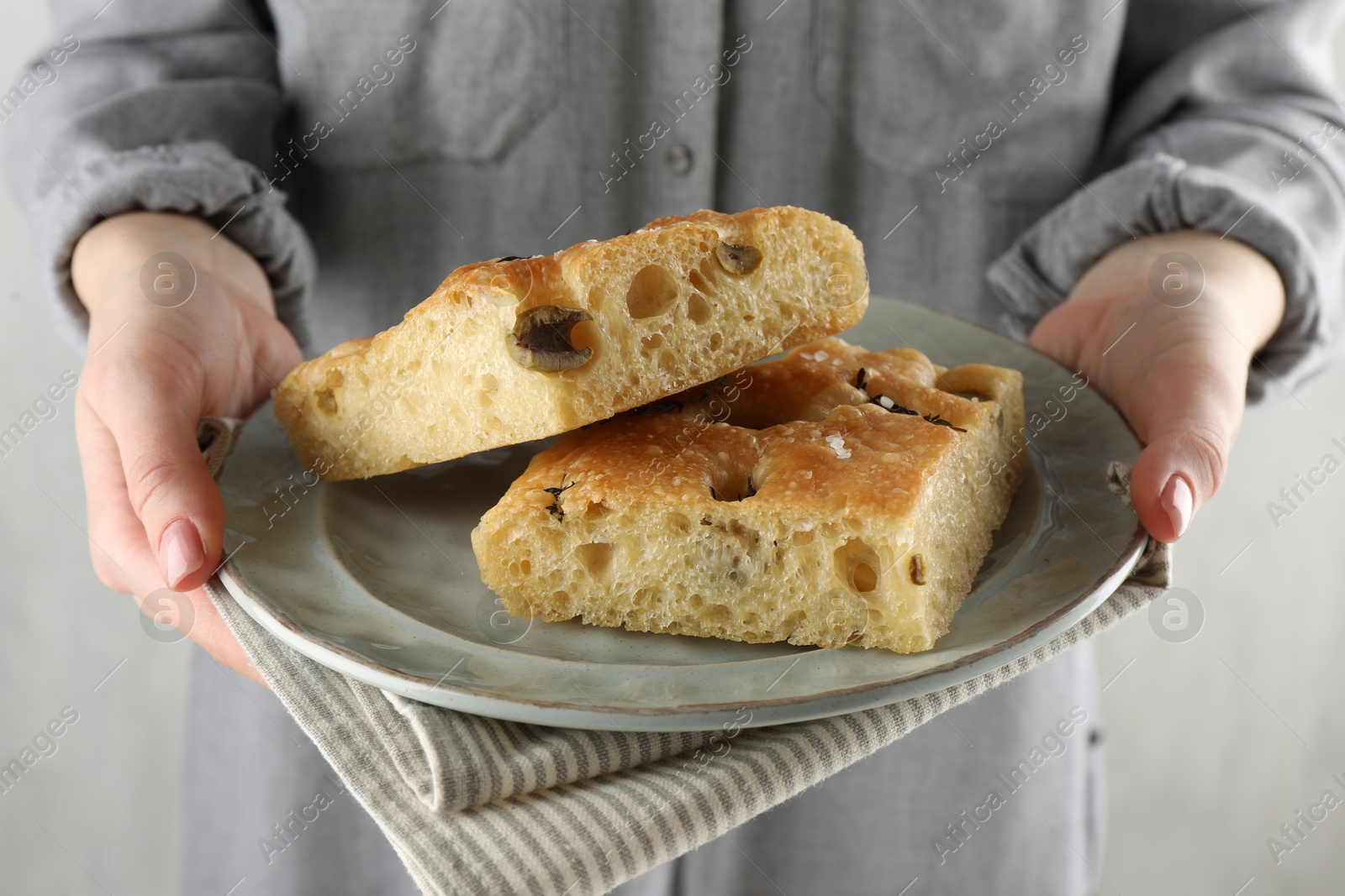 Photo of Woman with pieces of delicious focaccia bread on light background, closeup