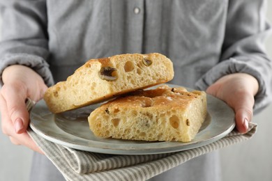 Photo of Woman with pieces of delicious focaccia bread on light background, closeup