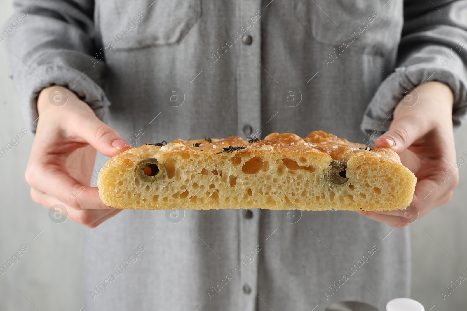 Photo of Woman with piece of delicious focaccia bread on light background, closeup