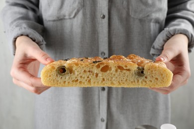 Photo of Woman with piece of delicious focaccia bread on light background, closeup