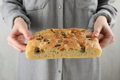 Photo of Woman with piece of delicious focaccia bread on light background, closeup