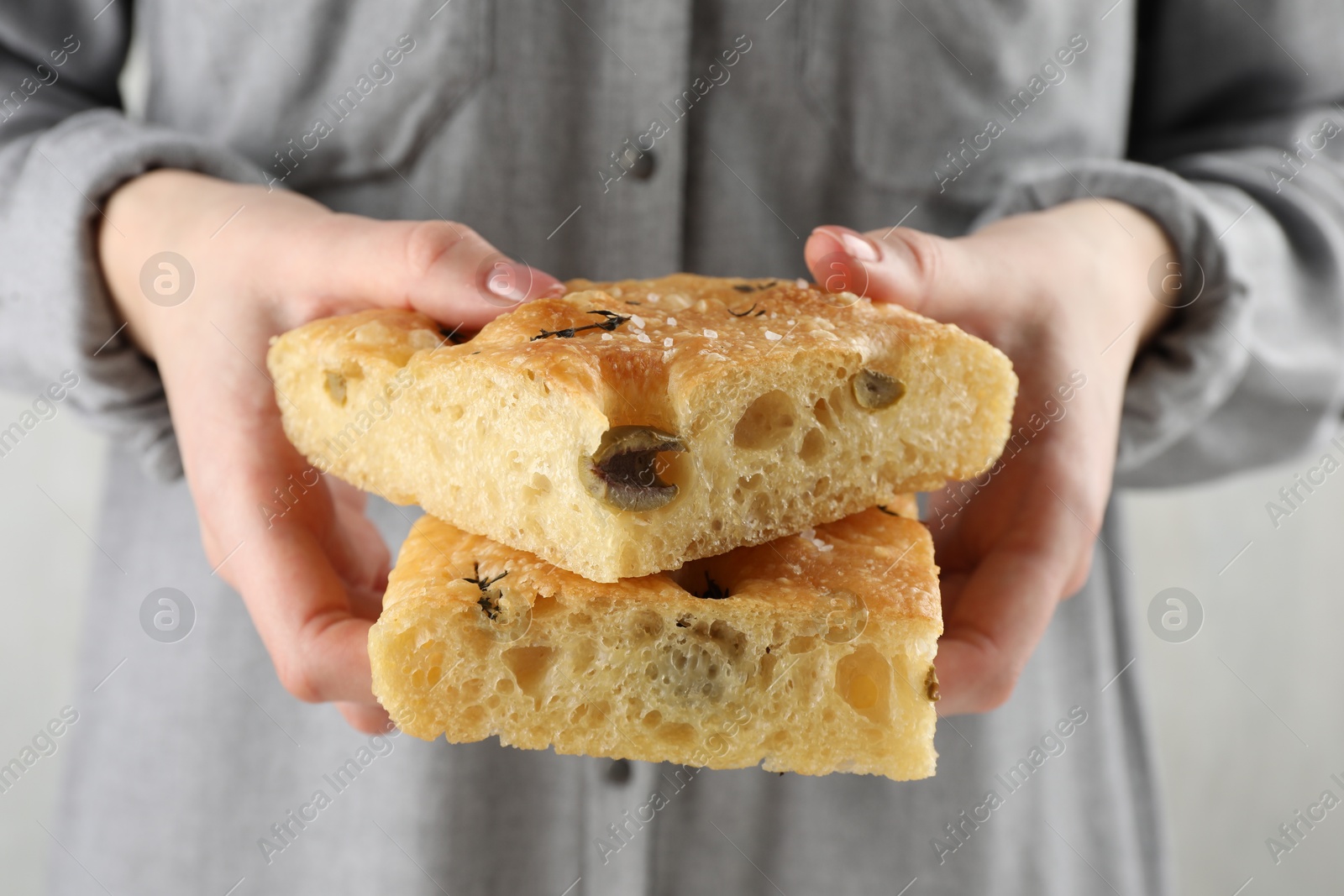 Photo of Woman with pieces of delicious focaccia bread on light background, closeup