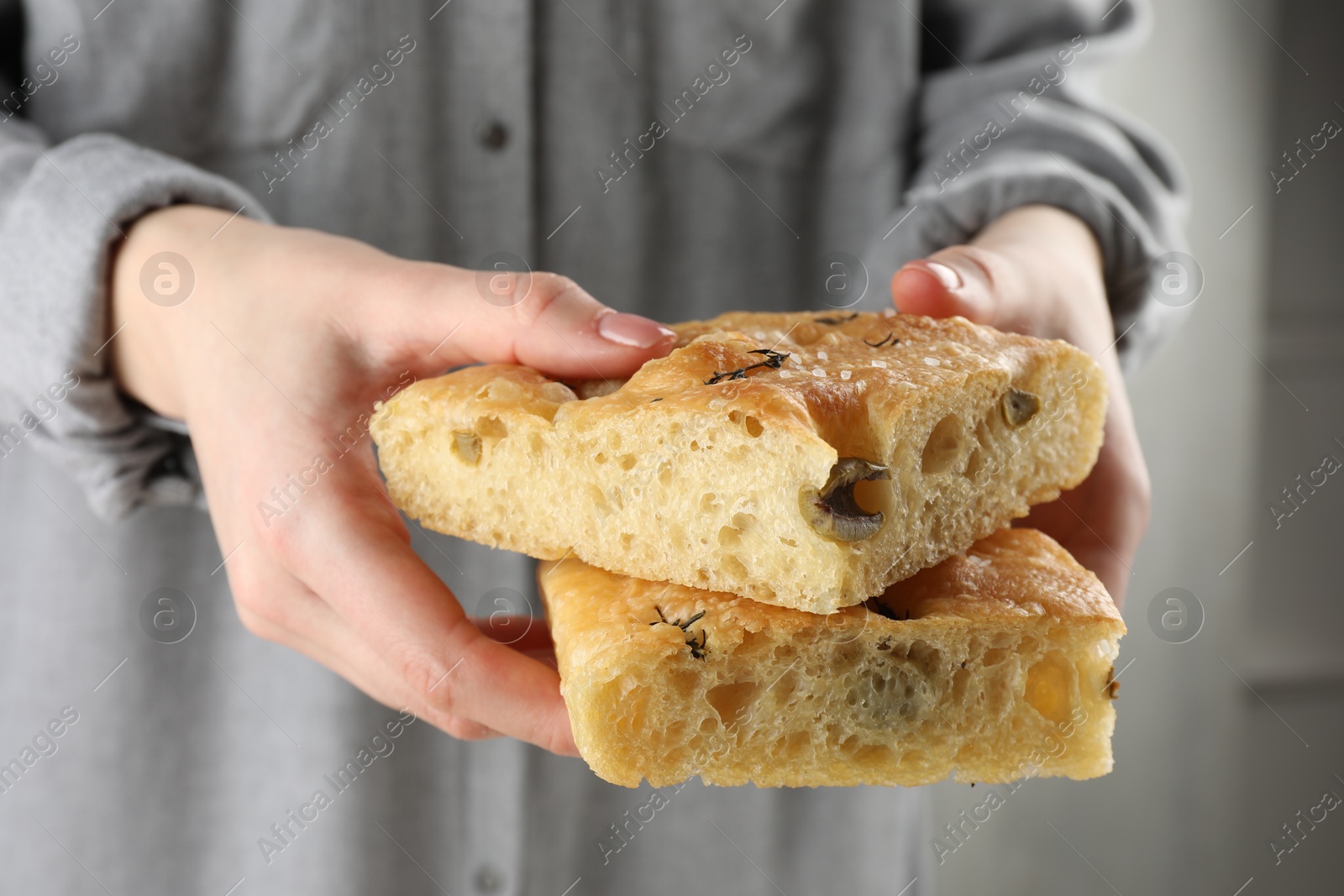 Photo of Woman with pieces of delicious focaccia bread on light background, closeup