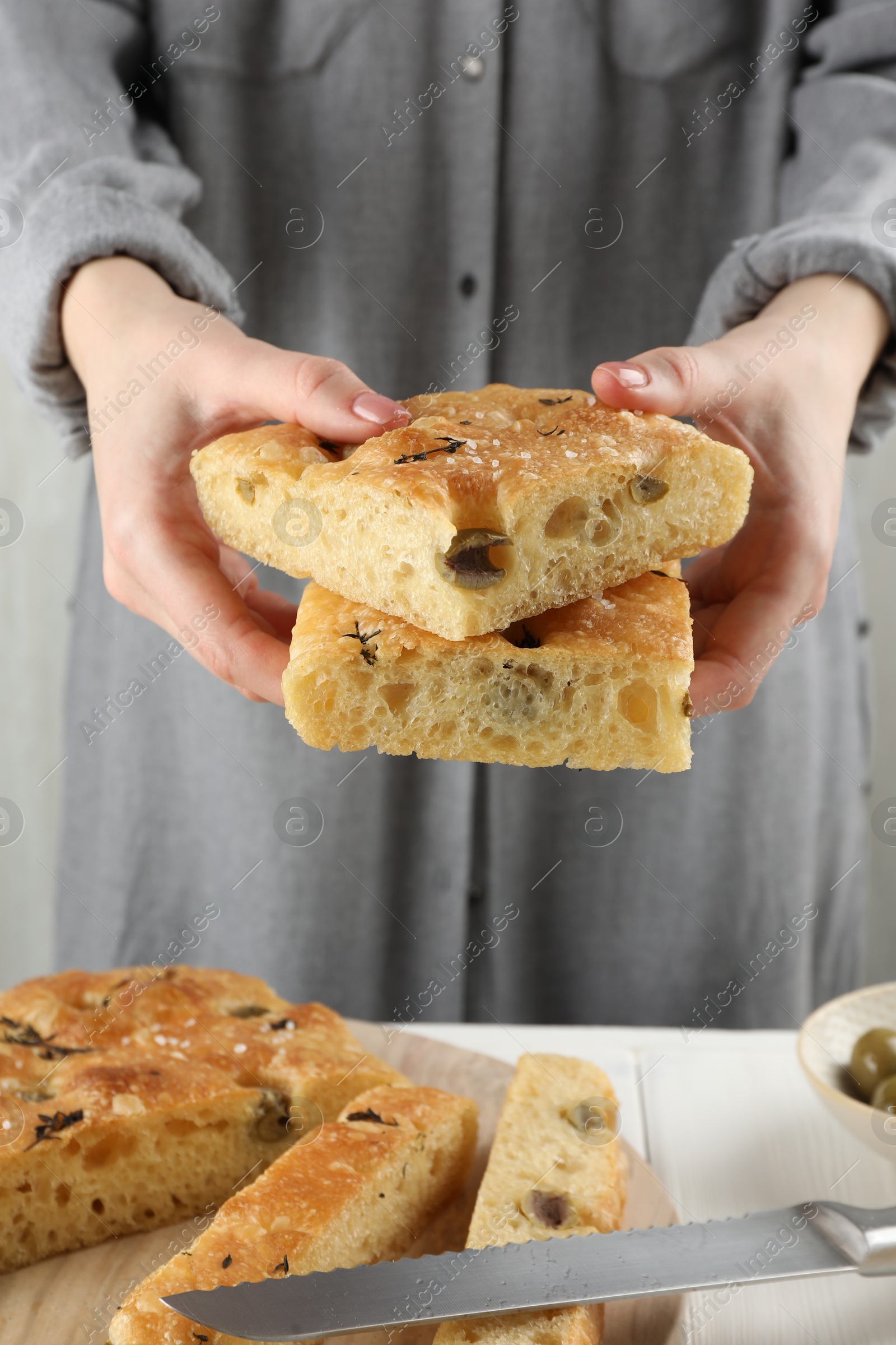 Photo of Woman with pieces of delicious focaccia bread at table, closeup