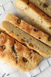 Photo of Slices of delicious focaccia bread with olives, thyme and salt on table, flat lay