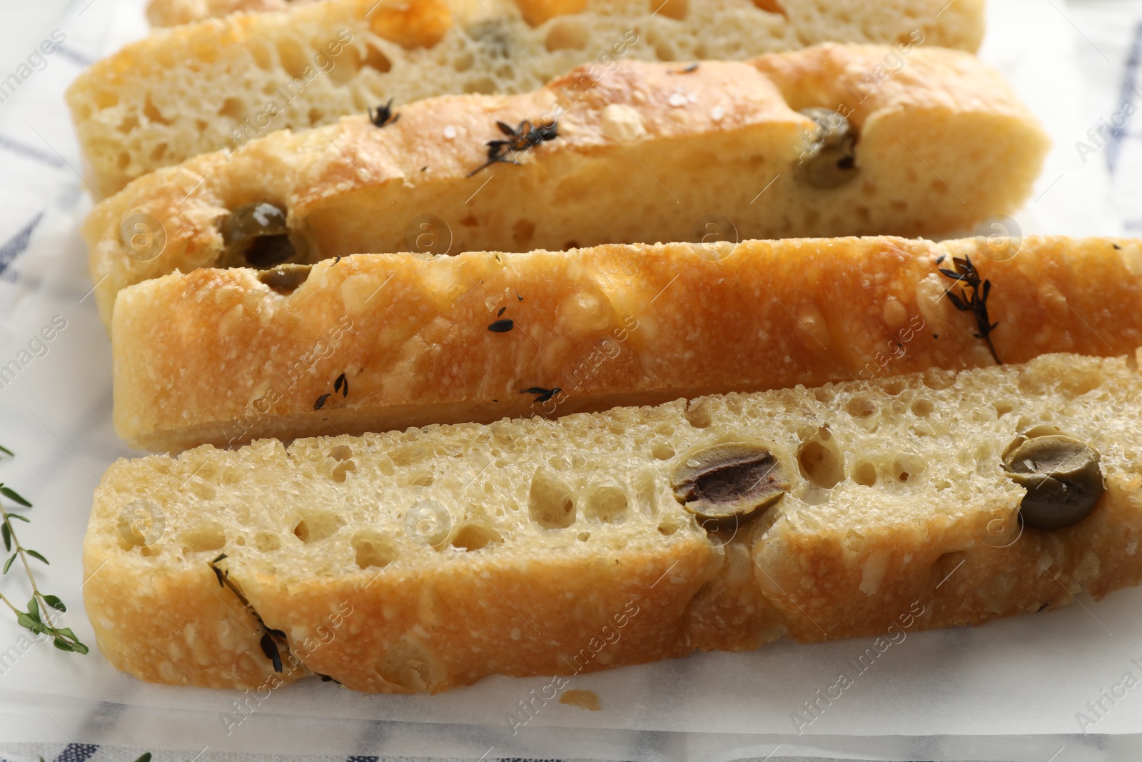 Photo of Slices of delicious focaccia bread with olives and thyme on table, closeup