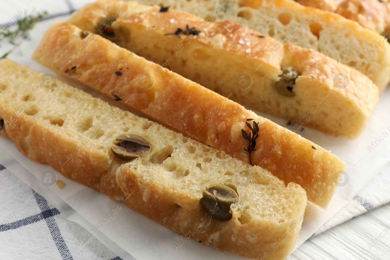 Photo of Slices of delicious focaccia bread with olives and thyme on table, closeup